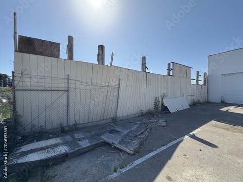Фотография A weathered dilapidated wooden boundary fence sitting in complete disrepair between adjacent commercial lots on Carmel Street in San Marcos, California