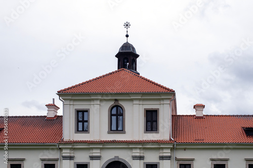 Historic Chapel With Red Tiled Roof, Bell Cupola and Cross Under Overcast Sky