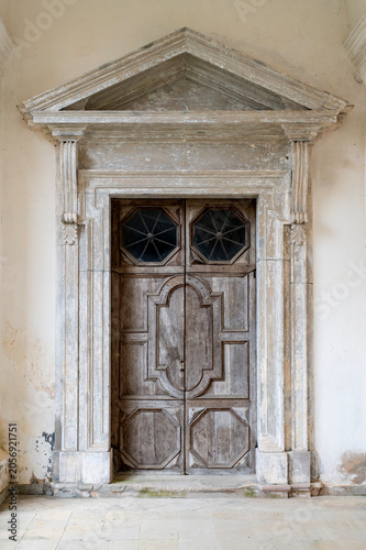Old Wooden Door and Weathered Stone Entrance With Ornate Classical Pediment and Rustic Panels