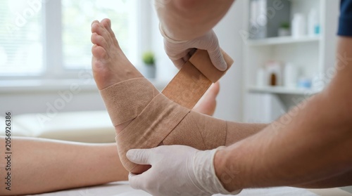 Medical Professional Applying Elastic Compression Wrap To Patient Ankle For Sprain Treatment In Clinical Setting