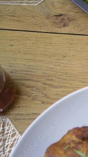 Vertical video: Sliding shot revealing roast poultry on gray tray at wood table, for dinner