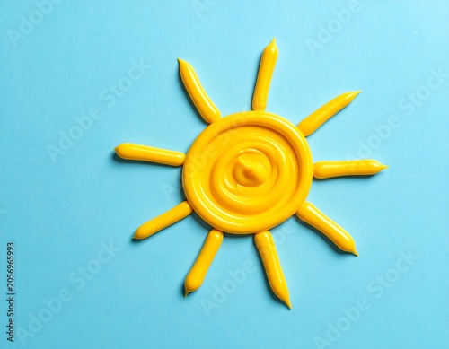 A bright yellow sun made of what appears to be plasticine on a light blue background