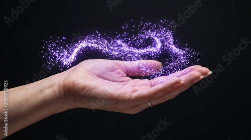 Hand with purple sparkling particles.