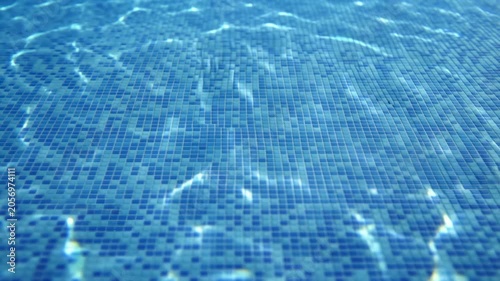 Blue swimming pool water with sunlight reflections over tiled mosaic