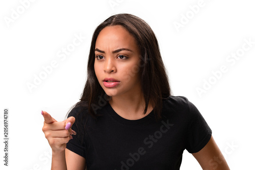 Angry young latina woman pointing away in fury isolated on white background.