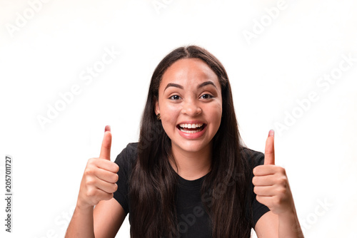 Enthusiastic young latina woman smiling and showing double thumbs up isolated on white background.