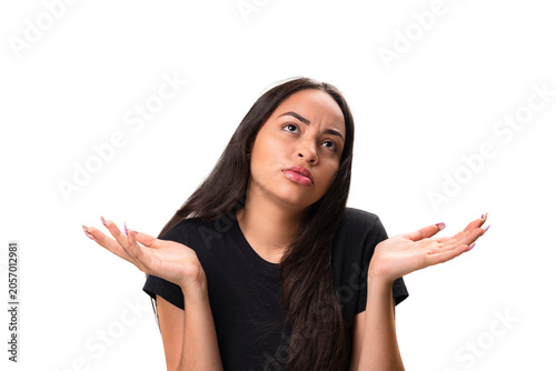 Confused young latina woman shrugging shoulders isolated on white background.
