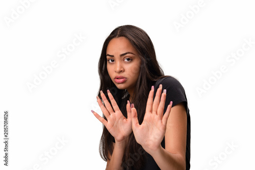 Scared young latina woman holding hands up in defense isolated on white background.