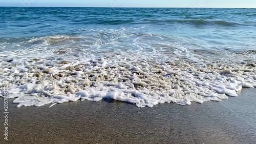 Slow motion of an ocean wave rolling onto the beach, closeup

