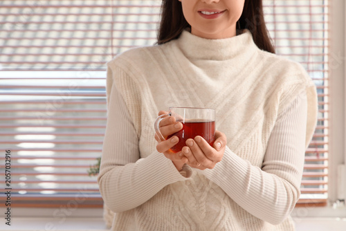 Woman in cozy sweater holdi...