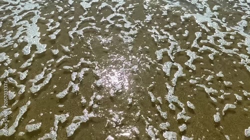 Slow motion of sea water with foam flowing in the shallow 
