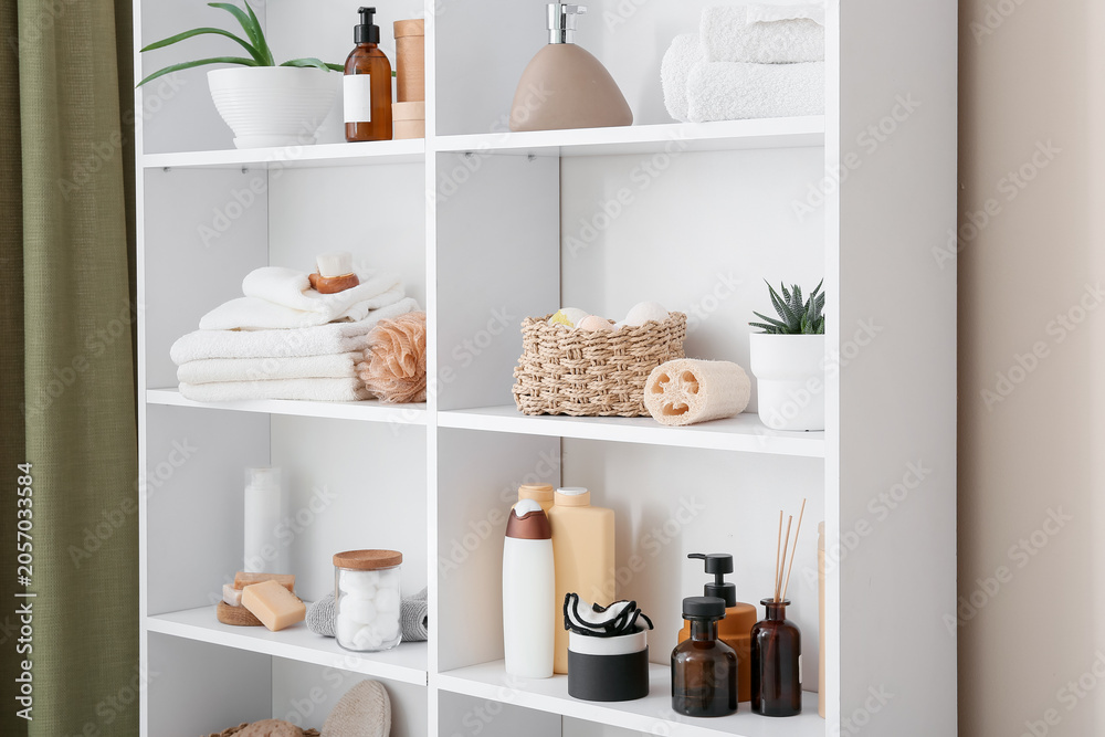 Fototapeta premium White bathroom shelf with skincare products, towels, and natural spa accessories for home organization