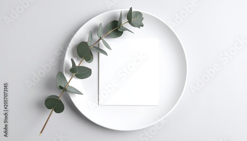 blank paper on white plate with eucalyptus leaves
