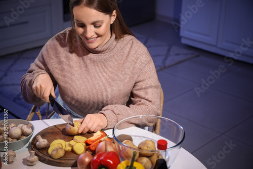 Young woman cutting potato ...