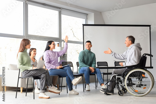 Male business speaker in wheelchair conducting seminar to people at office