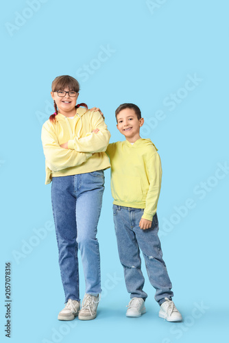 Cute girl with her brother in hoodies on blue background