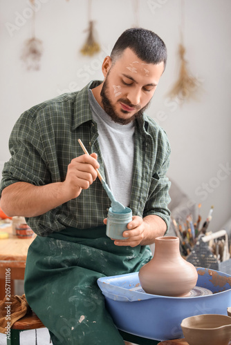 Young male potter mixing li...