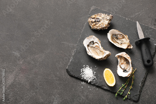 Φωτογραφία Fresh raw oysters on slate board with lemon, salt, and shucking knife, gourmet s
