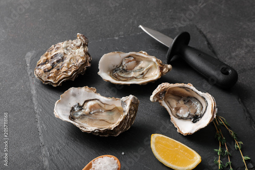 Φωτογραφία Fresh raw oysters on dark slate with lemon, salt, and shucking knife, gourmet se