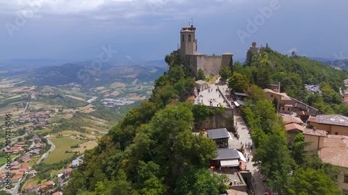 Aerial drone rise over medieval walls toward Cesta Tower, San Marino