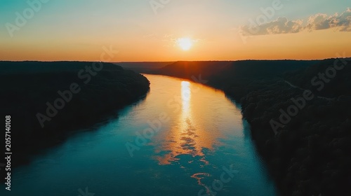 Serene sunset over a wide river valley casting golden light and vibrant reflections across the tranquil water