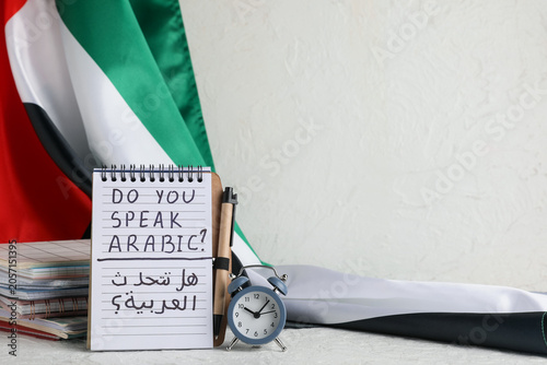 Foto Arabic language learning with notebook, pen, alarm clock, and UAE flag for educa