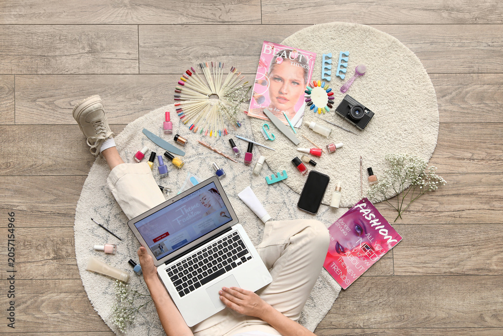 Naklejka premium Woman on floor with laptop, beauty products, and fashion magazines, online shopping and self-care lifestyle