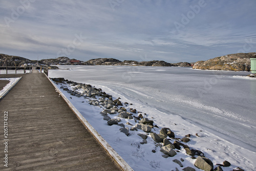 Konstfotografi Symmetrical view of a wooden pier with rope railings leading across the ice in Skrhamn