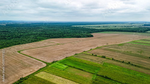 Картината върху платно Aerial panorama of patchwork fields with a wide freshly plowed tract beside green meadows and forests