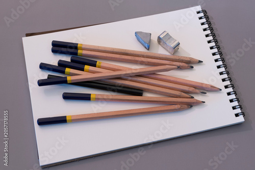 Several pencils arranged casually on a white sketch notebook with an eraser and sharpener.