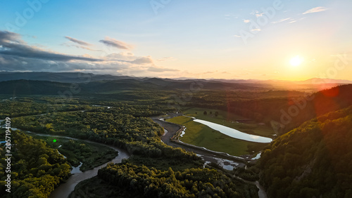 Aerial sunset over a winding river and forested hills