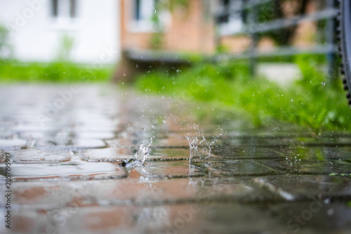 Low angle view of rain striking a glossy stone walkway and forming lively splashes in a residential courtyard