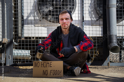 Homeless man and cardboard with text NO HOME NO FOOD on street
