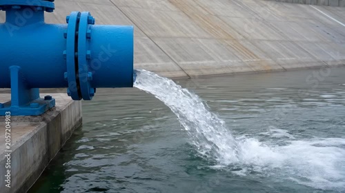 Industrial Blue Pipe Discharging Water into Concrete Canal.