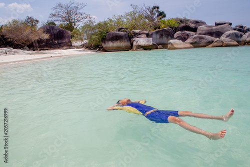 Obraz na plátně Young Boy Floating on Back in Clear Turquoise Sea Water at Tropical Beach