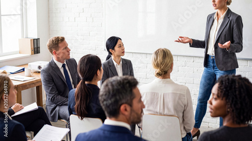 Фотография Photograph of a confident businesswoman giving a presentation to attentive colleagues in a bright office