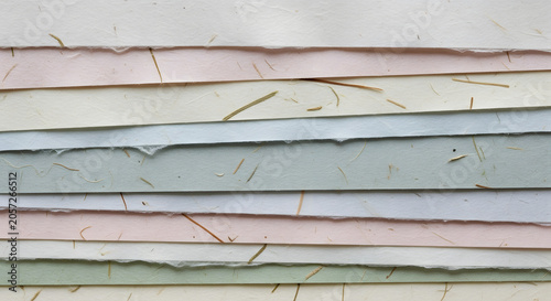A Stack of Handmade Paper Sheets: A close-up view showcases a stack of handmade paper sheets in various soft pastel colors, featuring a textured surface with visible fibers.