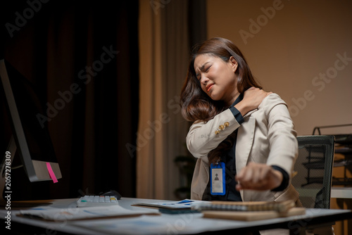 Asian businesswoman having neck pain working overtime in office