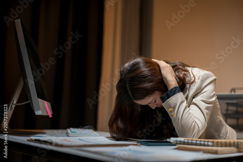 Stressed woman experiencing burnout working late at office desk