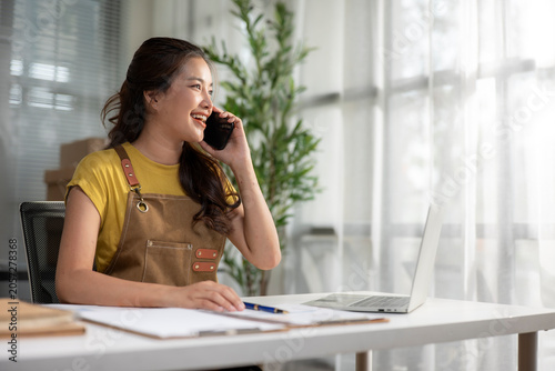 Woman talking on smartphone managing small business orders