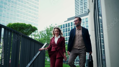 Business colleagues talking outside modern office building.