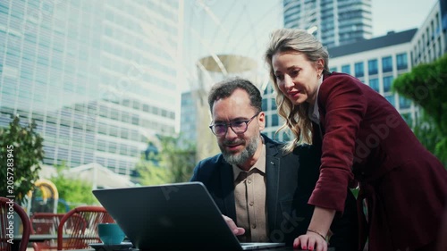 Business executives reviewing documents outside modern corporate building.