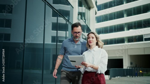 Business colleagues talking outside modern office building.