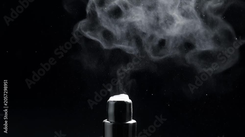 Misting bottle releasing spray dark background