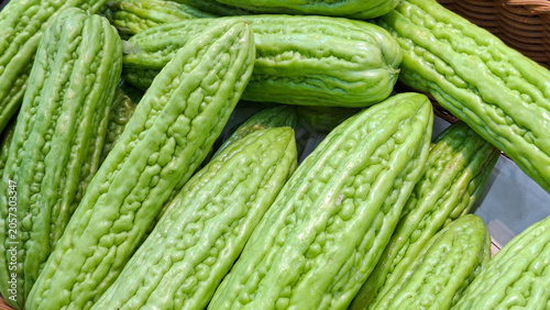 Slika na platnu Group of ripe bumpy bitter melon gourds neatly arranged in a wooden crate basket