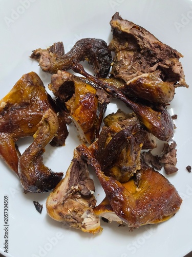 Roasted poultry quail in marinade seasoning or grilled partridge marinated in spices on machine gas stove for thai people eat in street market bazaar annual event festival in Nonthaburi city Thailand