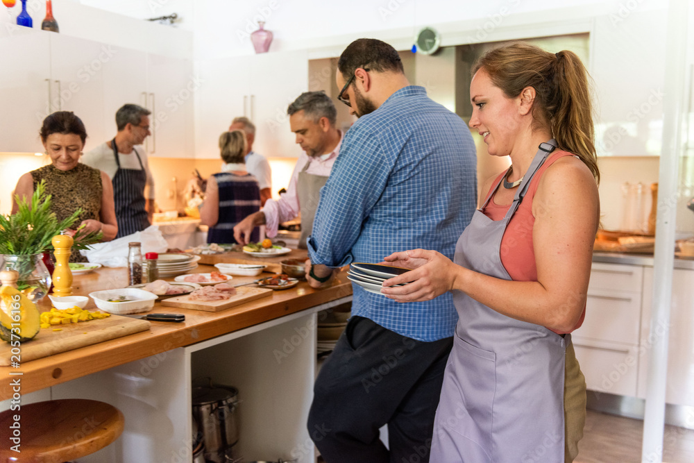 Obraz premium Group of people cooking together in a bright kitchen setting.
