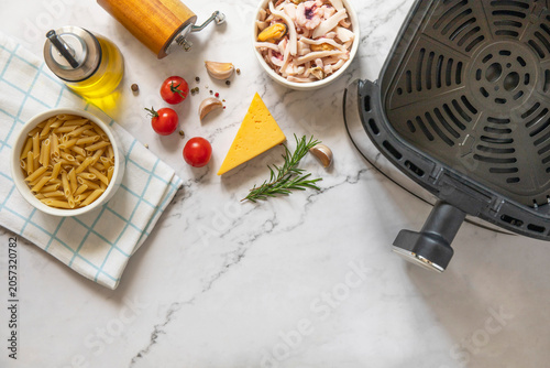 Foto Ingredients for pasta with seafood in creamy cheese sauce, in kitchen gadget modern white air fryer
