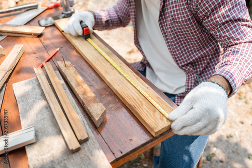 Obraz na plátne Portrait carpenter man working on DIY woodworking project at home workshop
