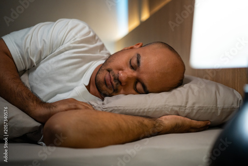 Canvastavla Young man lying in the bed at night